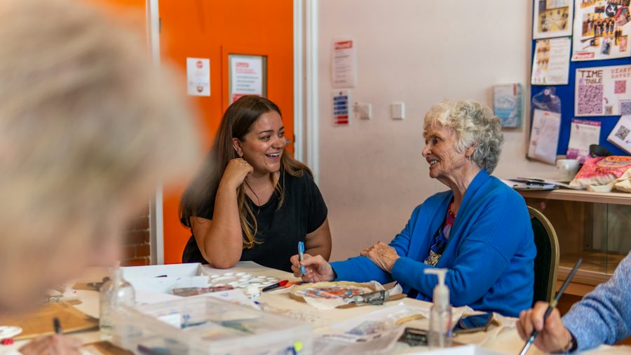Une jeune femme et une femme plus âgée discutent à une table