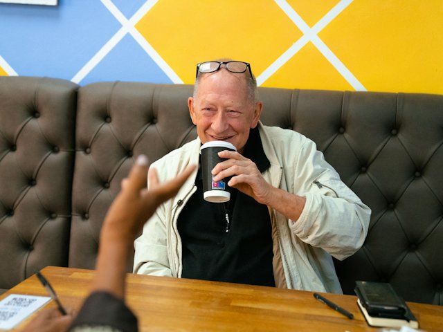 Un homme âgé boit un thé à une table, en bonne compagnie